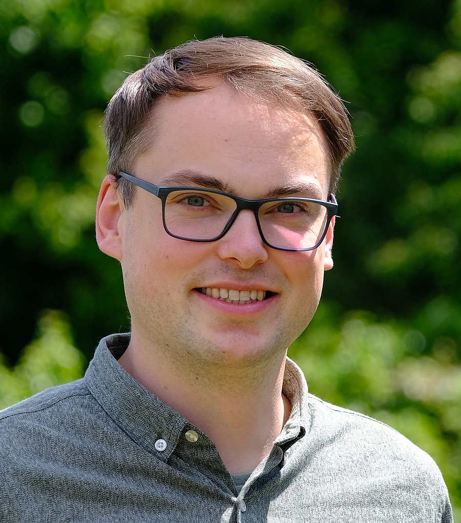 Accessibility description: white-male within mid-thirties, short brown-blond hair, black-framed glasses and green shirt.
