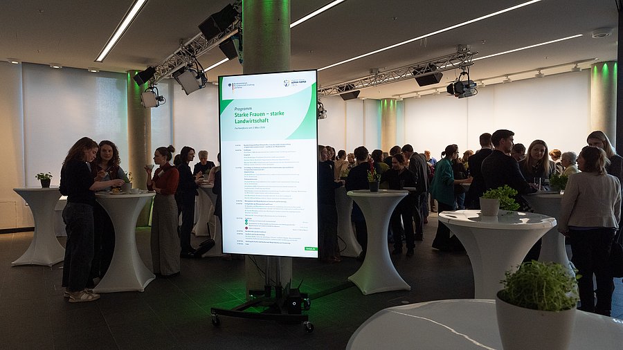 Teilnehmerinnen und Teilnehmer der Fachkonferenz „Starke Frauen – starke Landwirtschaft“ des Bundesministeriums für Landwirtschaft, Ernährung und Heimat vernetzen sich während einer Kaffeepause an Stehtischen.